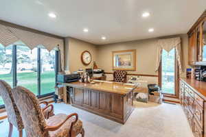 Home office with light colored carpet and recessed lighting