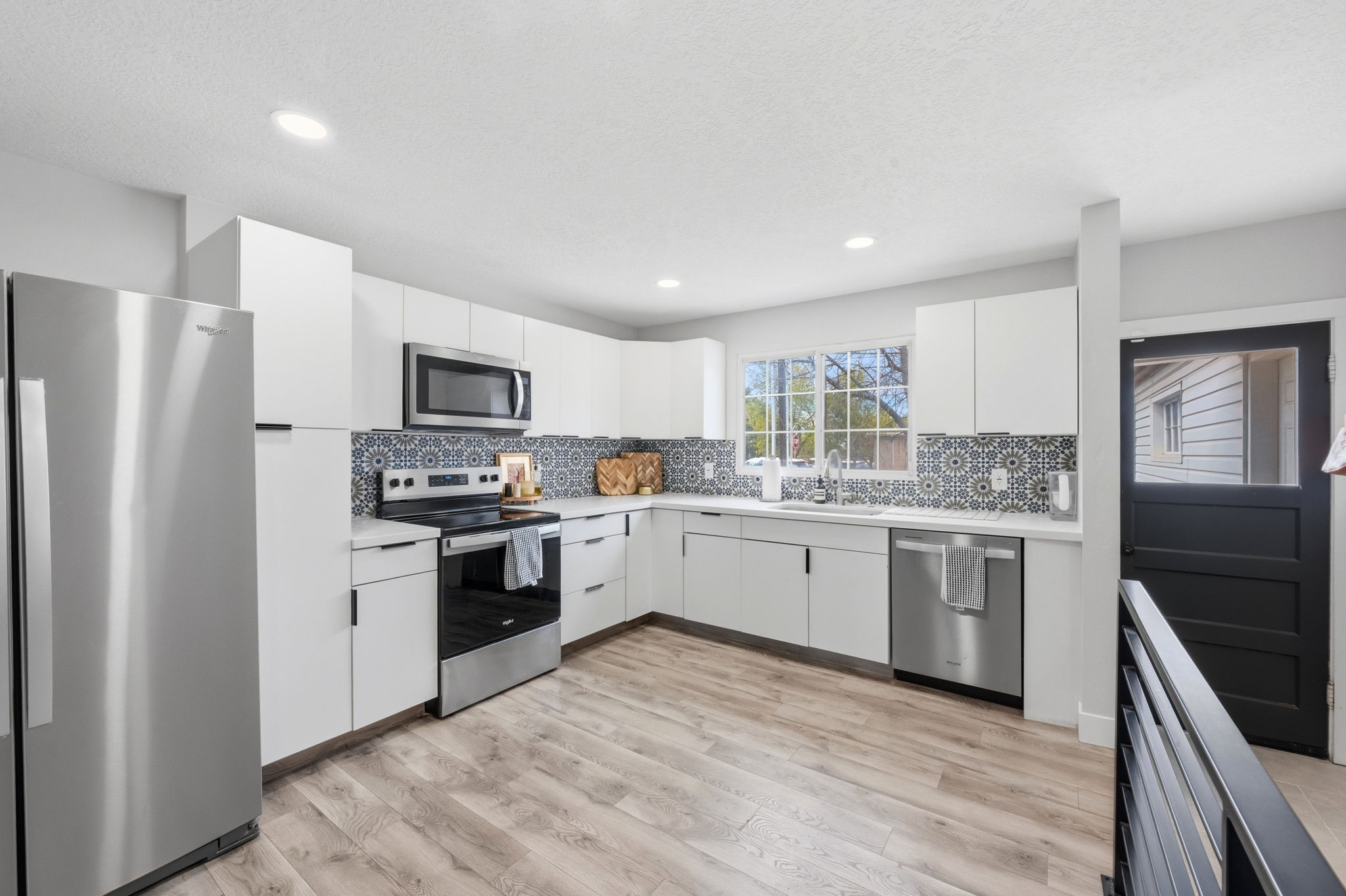 Kitchen featuring stainless steel appliances, white cabinets, light countertops, light wood finished floors, and modern cabinets