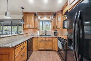 Kitchen with black appliances, light stone countertops, and nice oak  finish cabinets.