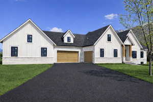 Modern farmhouse style home with board and batten siding, asphalt driveway, brick siding, an attached garage, and a front lawn