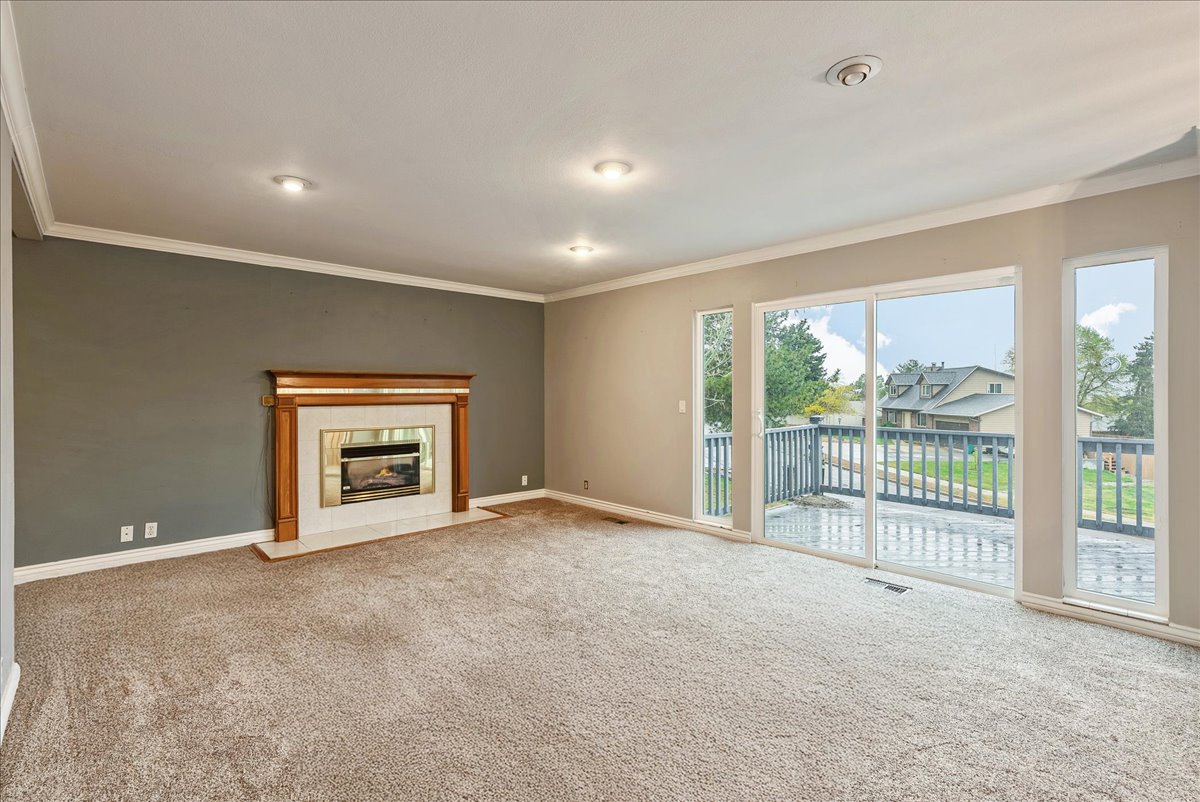 Unfurnished living room with carpet flooring, a fireplace, and ornamental molding