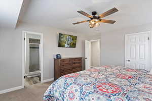 Bedroom with light carpet, a ceiling fan, and ensuite bathroom