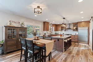 Kitchen with stainless steel built in refrigerator, a center island, light wood-style floors, glass insert cabinets, and wood finish cabinets