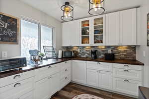 Butler Pantry Kitchen with wood counters, white cabinets, glass fronted cabinets, and stainless steel microwave
