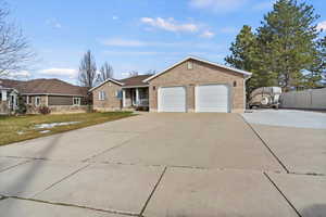 Single story home featuring brick siding, an attached garage, and RV parking
