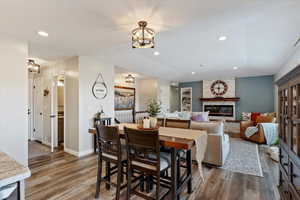 Dining space with a stone fireplace, wood finished floors, and recessed lighting