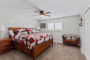 Bedroom featuring a closet, carpet, a ceiling fan, and a textured ceiling