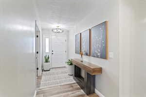 Foyer with a textured ceiling and light wood-style floors