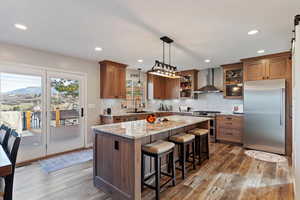 Kitchen with stainless steel appliances, hanging light fixtures, a breakfast bar, light stone counters, and light wood-style flooring