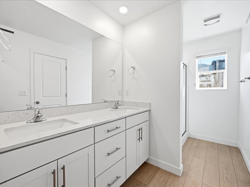 Primary en-suite bathroom with double vanity, a shower stall, and water closet