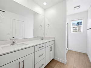 Primary en-suite bathroom with double vanity, a shower stall, and water closet
