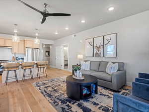 Living area with a ceiling fan, light wood-style floors, and recessed lighting