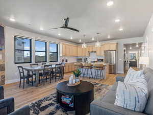 Living area with a ceiling fan, light wood-style flooring, and recessed lighting