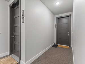 Doorway with baseboards and carpet floors