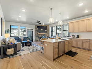 Kitchen featuring open floor plan, a fireplace, light countertops, light wood finished floors, and light wood finish cabinets
