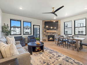 Living area featuring a ceiling fan, a fireplace, and light wood finished floors