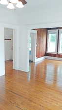 Spare room featuring light wood-style flooring, plenty of natural light, a ceiling fan, and wood walls