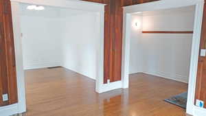 Empty room with hardwood / wood-style floors and wooden walls