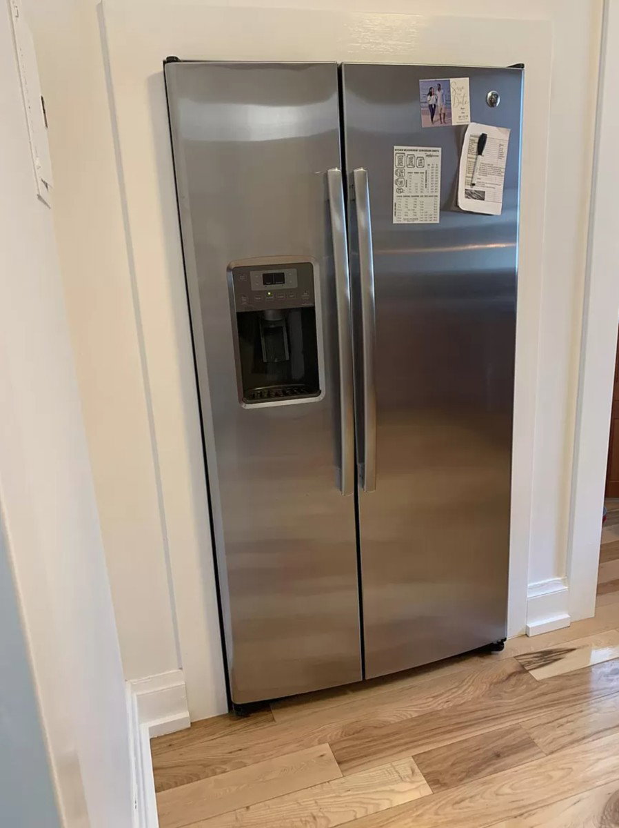 Kitchen view of stainless steel refrigerator with ice dispenser and light wood-style floors