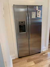 Kitchen view of stainless steel refrigerator with ice dispenser and light wood-style floors