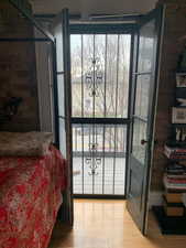 Bedroom with brick wall, light wood-type flooring, and access to outside
