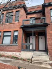 Doorway to property featuring brick siding and a porch