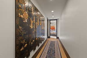 Hallway with light wood finished floors and recessed lighting leading to 2 additional guest suites.