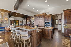 Kitchen with a breakfast bar area, recessed lighting, vaulted ceiling, open floor plan, and glass insert cabinets