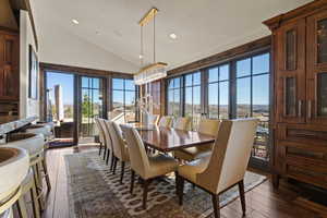 Dining area with dark wood-style floors, vaulted ceiling, and recessed lighting