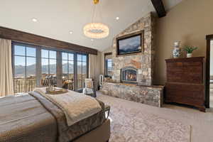 Bedroom with lofted ceiling, access to exterior, a fireplace, and suspended lighting