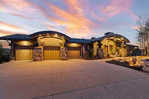 View of front facade featuring an attached garage, concrete driveway, and stone siding