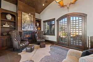 Living area featuring french doors, lofted ceiling, arched walkways, recessed lighting, and a tile fireplace