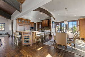 Dining room featuring vaulted ceiling, wine cooler, dark wood-type flooring, recessed lighting, and arched walkways