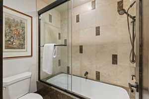 Queen Guest Full bathroom with combined bath / shower with glass door and toilet