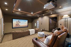 Cinema room featuring stadium seating recessed lighting, carpet, and a raised ceiling