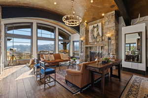 Living room featuring a mountain view, plenty of natural light, a high barrel ceiling, a fireplace, and dark wood-style flooring