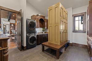 Laundry area with stacked washer / dryer, cabinet space, and vaulted ceiling