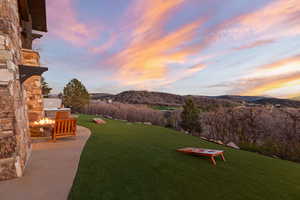 Yard at dusk with a mountain view, a yard, a fire pit, and a patio area