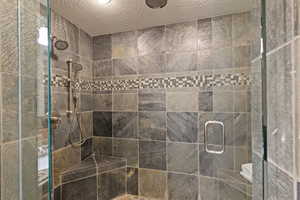 King Guest Bathroom featuring a shower stall and a textured ceiling
