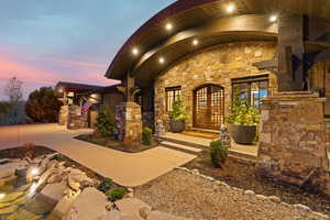 Doorway to property featuring stone siding, french doors, and a metal roof
