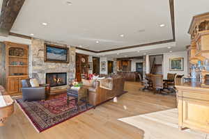 Living area with a fireplace, built in features, light wood-style flooring, a tray ceiling, and recessed lighting