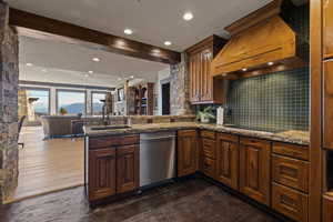 Kitchenette/Bar with dark stone counters, dishwasher, ice maker, range, microwave, fridge, decorative backsplash, open floor plan, and recessed lighting