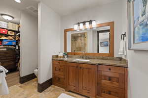 Bear bedroom bathroom with vanity, a spacious closet, a shower stall, stone tile flooring, and recessed lighting