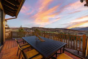 Balcony at dusk with outdoor dining space and a deck with mountain view