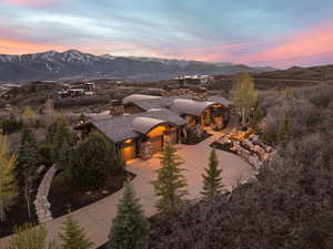 View of front facade featuring a chimney, a mountain view, concrete driveway, stone siding, and an attached garage