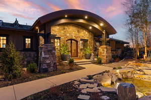 View of exterior entry featuring stone siding, a small pond, and board and batten siding