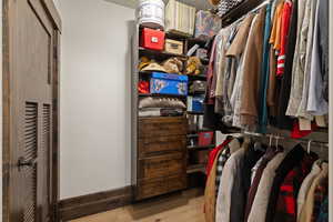 Bear bedroom walk in closet with light wood-type flooring