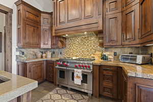 Kitchen featuring double oven range, vaulted ceiling, and decorative backsplash