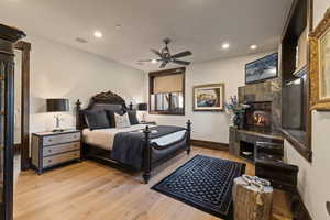 King Guest Bedroom with a fireplace, light wood-style floors, recessed lighting, and a ceiling fan