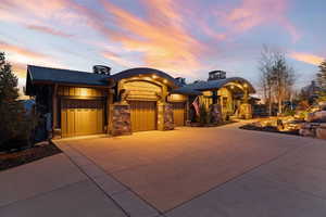View of front of house featuring a garage, concrete driveway, and stone siding